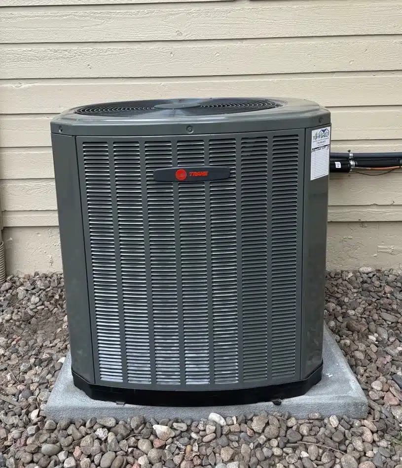 Trane central air conditioner installed on a concrete pad by Top Shelf Electric Heating & Plumbing in Denver, CO